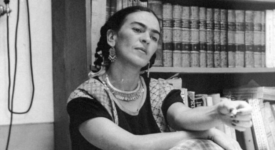 Fotografía de Frida Kahlo con libros en el fondo