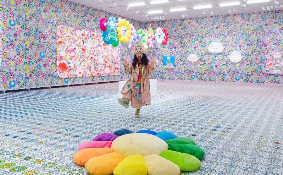 El artista japones parado en una sala de exhibición con sus obras
