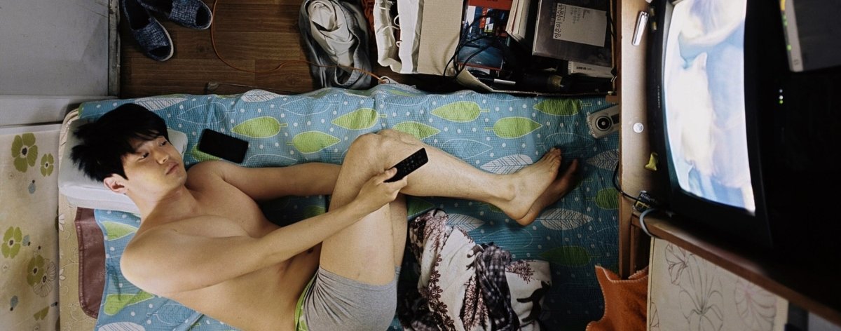 Fotografía de un hombre viviendo en un "Goshitel" por Sim Kyu Dong