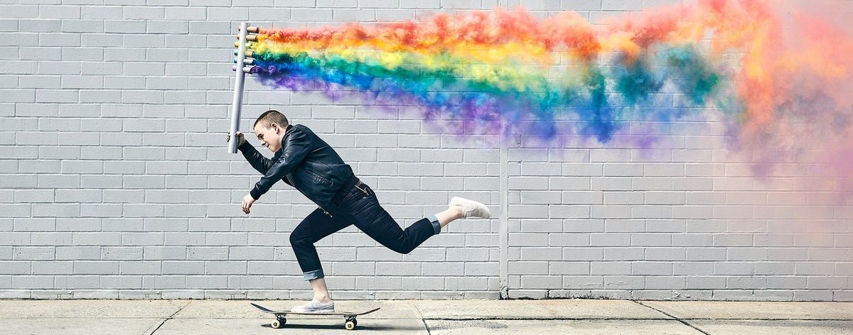 Skater Queer patinando con una bandera gay de humo