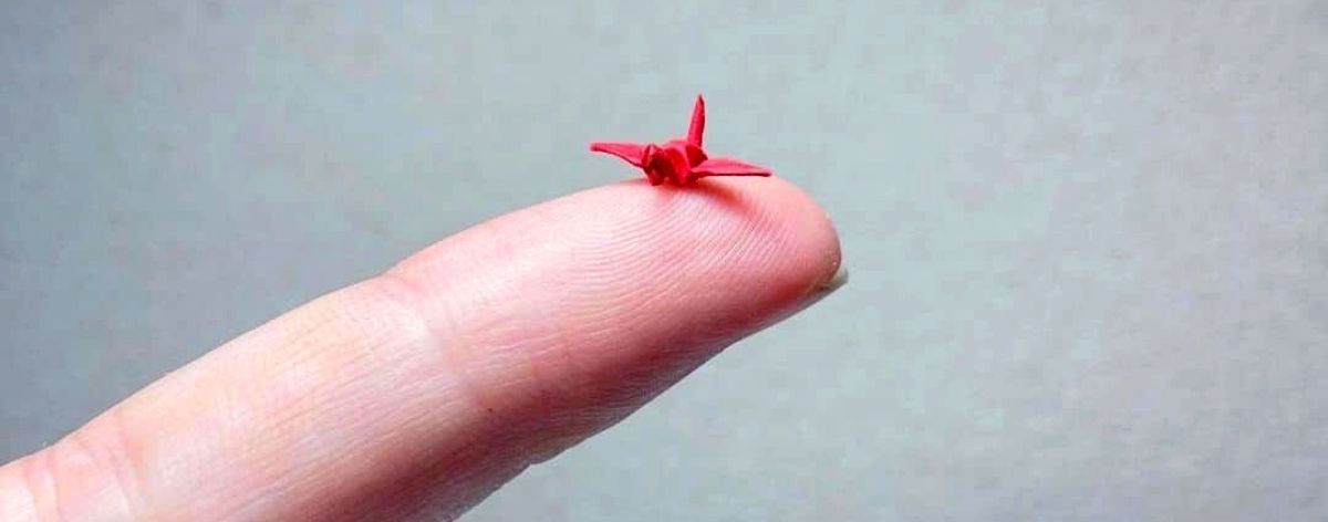 dedo sostiene figura de papel roja miniatura